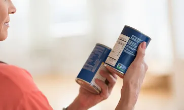 Mujer examinando latas de comida con la etiqueta de No-GMO